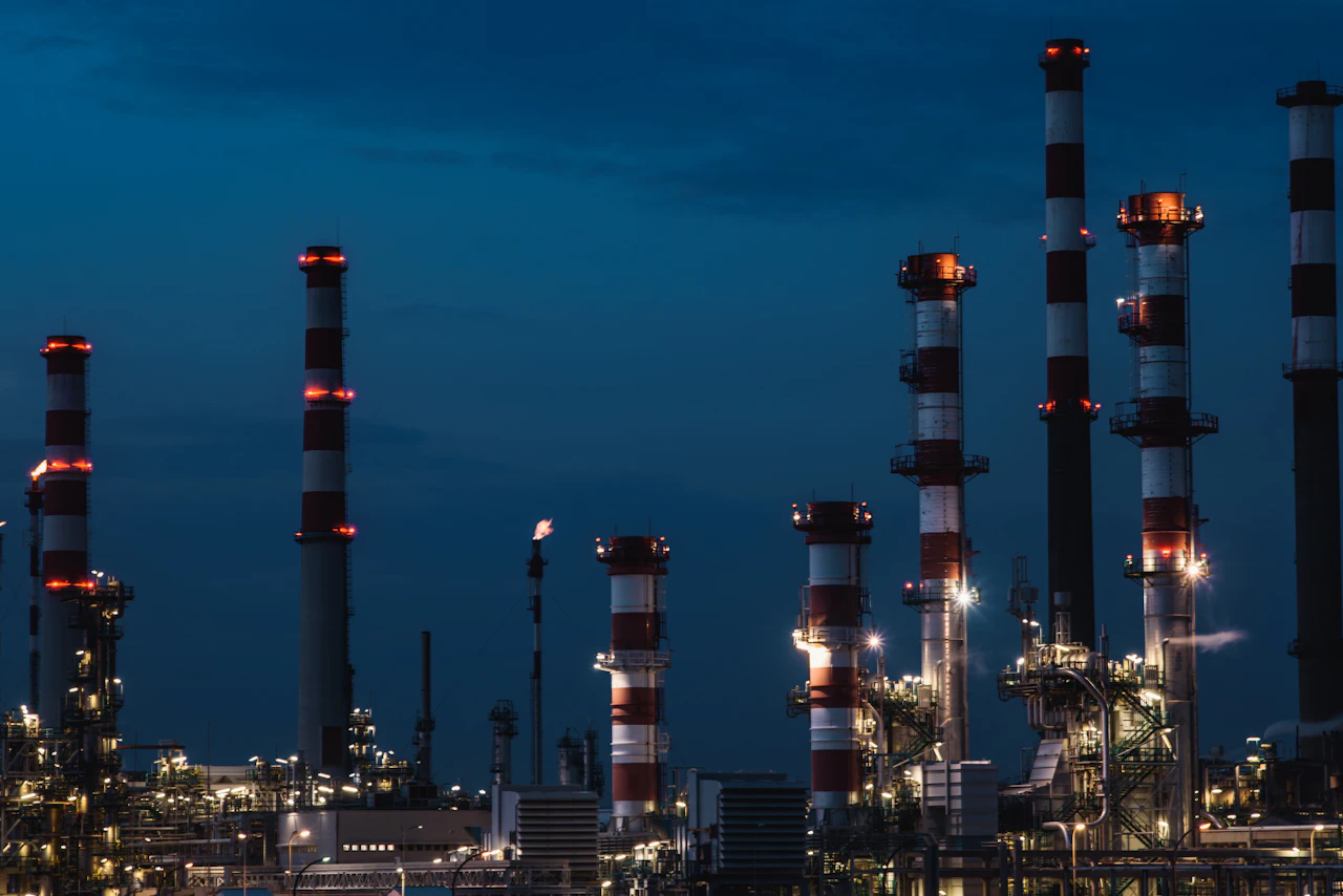 An oil refinery with illuminated stacks at dusk