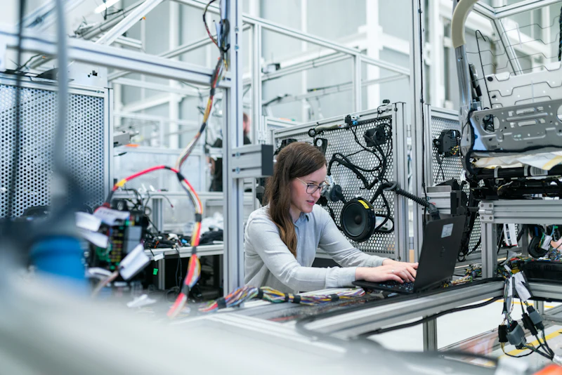 An engineer working on a laptop inside an automated production cell
